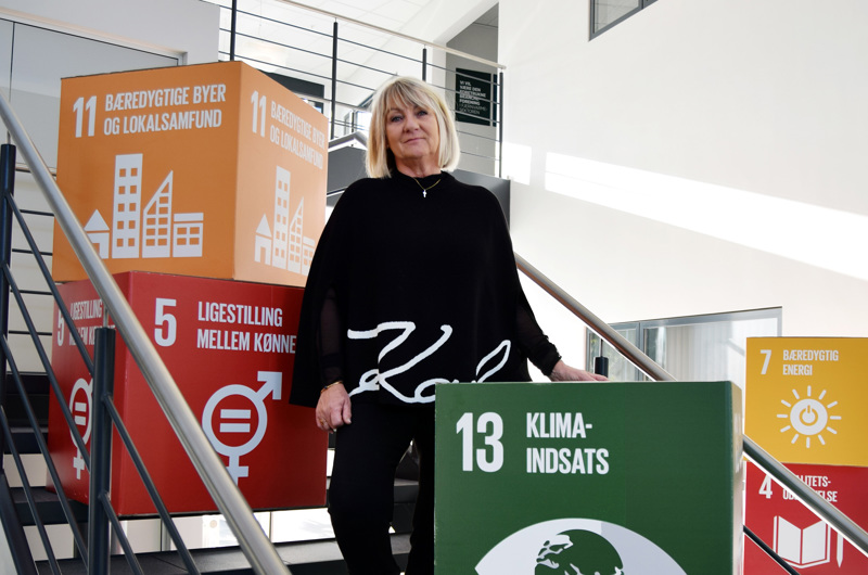 Tina Maria Lund Kristensen, chefkonsulent hos Dansk Fjernvarme med flere papkasser, der viser verdensmålene