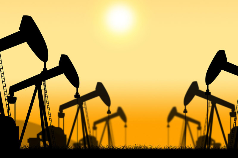 genrebillede af oliefelt på land med pumperne i silhouet mod gylden himmel